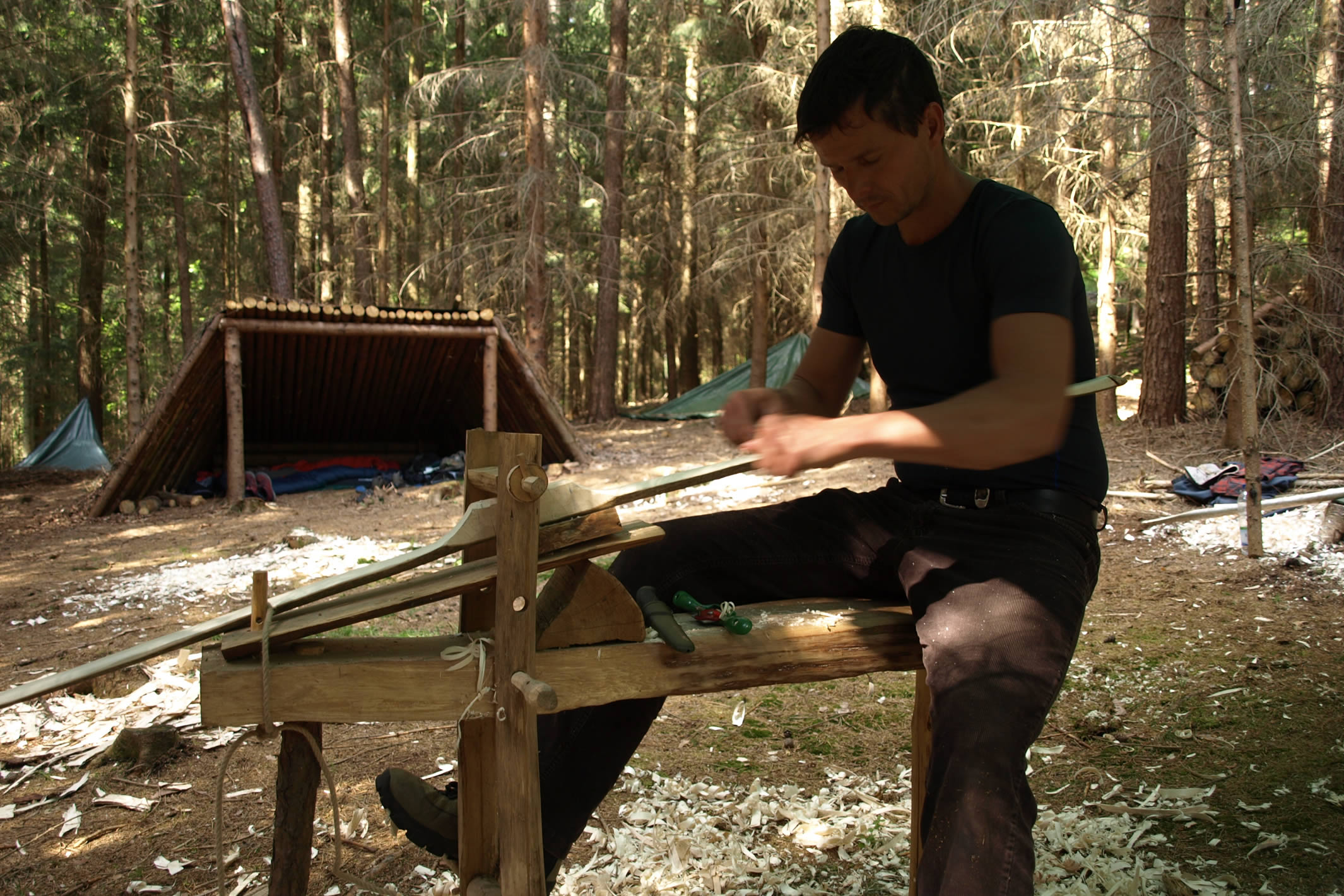 Mann baut einen Bogen in der Wildnis