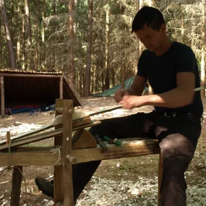 Mann baut einen Bogen in der Wildnis